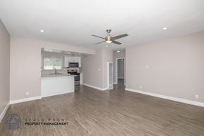 Hawthorne apartment for rent - A spacious room with a ceiling fan and wooden flooring.