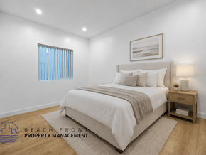 Long Beach apartment for rent - A bedroom with a large bed, a nightstand, and a window with blue curtains.