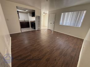 Hawthorne apartment for rent - A spacious room with wooden flooring and white walls.