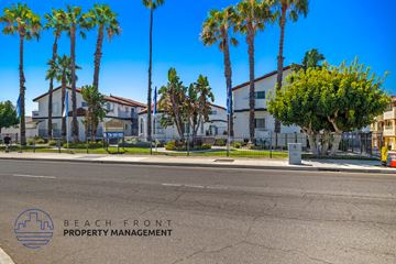 Anaheim apartment for rent - A street view with palm trees and a sign for Beach Front Property Management.