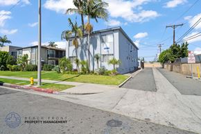 Gardena apartment for rent - A street view of a residential area with a building and palm trees.