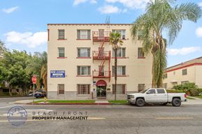 Los Angeles apartment for rent - A white building with a sign that says "Now Leasing" in front of it.