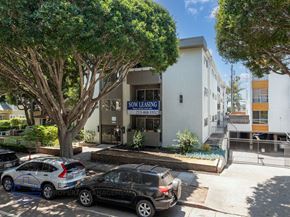 Santa Monica apartment for rent - A parking lot with cars and a building that says "NOW LEASING" in front of it.