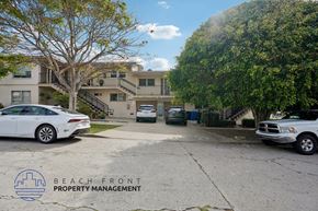 San Pedro apartment for rent - A white car is parked in front of a building with the logo of Beach Front Property Management.