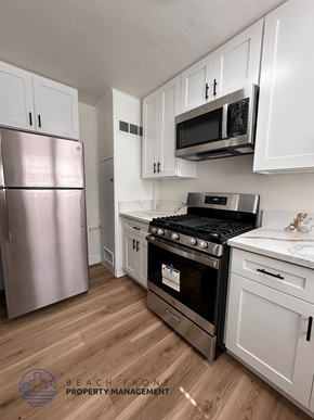 Santa Ana apartment for rent - A kitchen with a stainless steel refrigerator, a stove, and white cabinets.