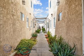 Long Beach apartment for rent - a walkway between two buildings with plants on the side