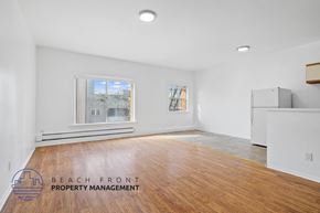 Los Angeles apartment for rent - A spacious room with wooden flooring and a large window overlooking a beachfront.