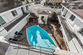 Hawthorne apartment for rent - A pool surrounded by apartment buildings with a sign for beach property management.