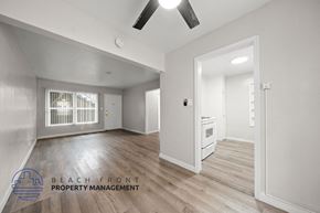 Long Beach apartment for rent - A spacious room with a fan and a window with bars.