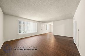 Paramount apartment for rent - A spacious room with wooden flooring and white walls, with a window covered by white blinds.