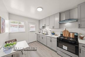 Anaheim apartment for rent - A kitchen with a stove top oven and a dining table with a bowl of fruit on it.