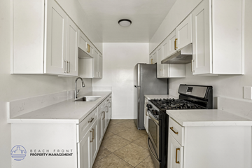 Long Beach apartment for rent - A kitchen with white cabinets and a black stove top oven.