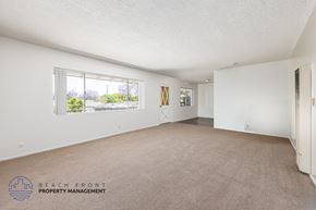 South Gate apartment for rent - A spacious room with a carpeted floor and a window overlooking a beach.