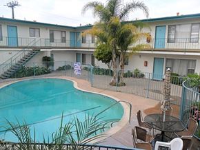Gardena apartment for rent - a swimming pool with a palm tree in front of a building