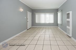 Long Beach apartment for rent - A spacious room with tiled flooring and a window with blinds.