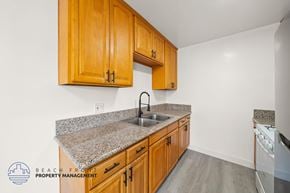 Gardena apartment for rent - A kitchen with granite countertops and wooden cabinets.