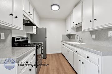 Santa Ana apartment for rent - A kitchen with white cabinets and a black stove top oven.