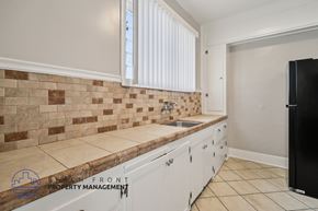 Long Beach apartment for rent - A kitchen with a black fridge and white cabinets.