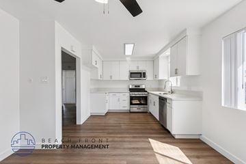 San Pedro apartment for rent - A spacious kitchen with white cabinets and a wooden floor.