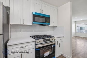 Hawthorne apartment for rent - A kitchen with white cabinets and a blue microwave.