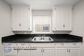 Long Beach apartment for rent - A kitchen with white cabinets and a black countertop.