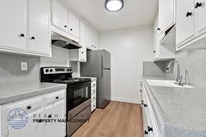 Santa Ana apartment for rent - A kitchen with white cabinets and a black stove top oven.