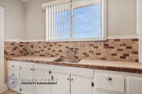 Long Beach apartment for rent - A kitchen with a brick backsplash and white cabinets.
