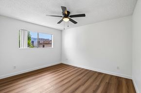 San Pedro apartment for rent - A room with a ceiling fan and a window showing a view of a house.