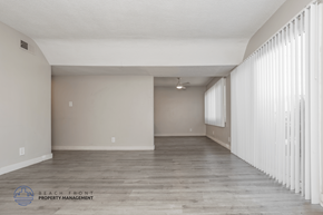 Hawthorne apartment for rent - A spacious room with wooden flooring and white curtains on the window.