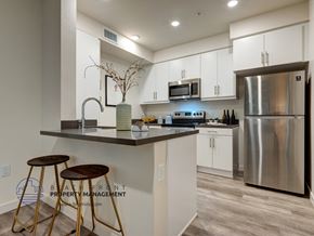 Los Angeles apartment for rent - A modern kitchen with a bar stool and a stainless steel refrigerator.