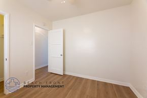 Long Beach apartment for rent - a bedroom with white walls and wood floors and a white door