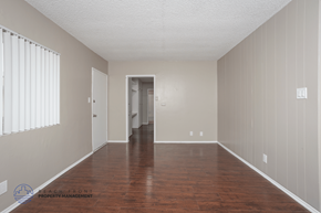 Hawthorne apartment for rent - A spacious room with wooden floors and white walls.