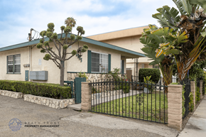 Hawthorne apartment for rent - A house with a green fence and a tree in front.