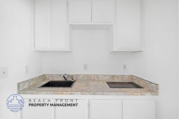 San Pedro apartment for rent - A kitchen with a marble countertop and white cabinets.