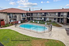 Whittier apartment for rent - A swimming pool is surrounded by a fence in a courtyard.
