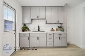 Buena Park apartment for rent - A kitchen with white cabinets and a countertop with a plant on it.