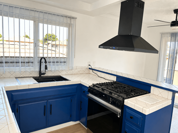 Westminster apartment for rent - A kitchen with blue cabinets and a black range hood.
