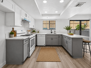 Westminster apartment for rent - A modern kitchen with white cabinets and a wooden floor.