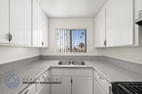 Los Angeles apartment for rent - A kitchen with white cabinets and a view of a beach through the window.