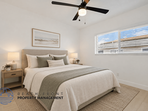 Buena Park apartment for rent - A bedroom with a large bed, a ceiling fan, and a nightstand with a plant on it.