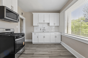 Long Beach apartment for rent - A kitchen with white cabinets and a black stove top oven.