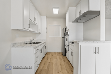Gardena apartment for rent - A kitchen with white cabinets and appliances, and a logo for Beach Front Property Management in the bottom left corner.