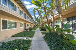 Inglewood apartment for rent - A long concrete walkway leads between two rows of buildings with balconies.