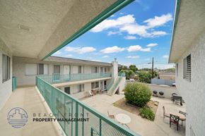Hawthorne apartment for rent - A balcony of a building with a green railing and a logo for Beach Front Property Management.