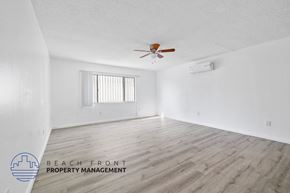 San Pedro apartment for rent - A spacious room with a ceiling fan and wooden flooring.