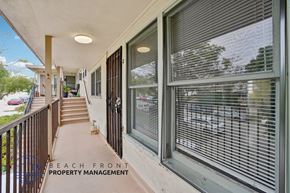 San Pedro apartment for rent - A balcony with a view of the beach and a sign for Beach Front Property Management.