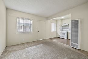 Wilmington apartment for rent - A spacious living room with a window, a door, and a kitchen area with a refrigerator, oven, and microwave.