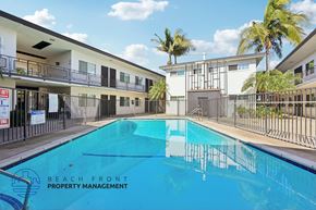 Hawthorne apartment for rent - A swimming pool in front of a building with the words Beach Front Property Management.
