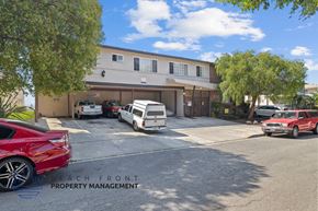 Gardena apartment for rent - A red car is parked in front of a building with the sign "Beach Front Property Management".