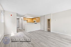 Santa Ana townhouse for rent - A spacious room with wooden flooring and a logo for Beach Front Property Management.
